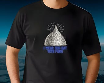 May include: Black t-shirt featuring a graphic of a foil hat with radiating lines and the text "I WEAR THIS HAT WITH PRIDE" in blue. The design is centered on the chest.