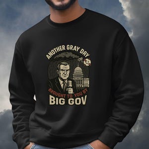 May include: Black sweatshirt with a graphic featuring a man holding a microphone, the U.S. Capitol building, and the text "ANOTHER GRAY DAY BROUGHT TO YOU BY BIG GOV." The design includes rain and a stylized bomb.