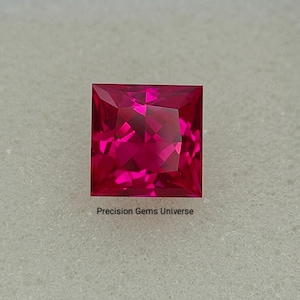 Puede incluir: Una gema rosa vibrante de corte cuadrado con múltiples facetas. La gema está sobre un fondo neutro. El texto "Precision Gems Universe" está en la parte inferior.