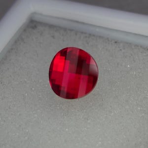 May include: A round, red gemstone with a faceted, striped pattern.
