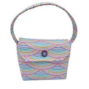 May include: A small, white fabric handbag with a rainbow-colored pattern and a purple button closure. The bag has a single, fabric handle.