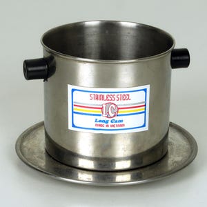 May include: Stainless steel Vietnamese coffee filter with a black plastic handle and a label that reads "Stainless Steel Long Cam Made in Vietnam".