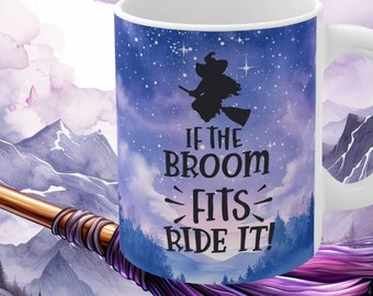 May include: A white ceramic mug with a blue and purple watercolor design featuring a silhouette of a witch flying on a broomstick. The text "If the broom fits ride it!" is printed on the mug.