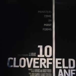 Puede incluir: Un p&oacute;ster de pel&iacute;cula para la pel&iacute;cula "10 Cloverfield Lane" con el t&iacute;tulo en texto blanco sobre fondo negro. El p&oacute;ster tambi&eacute;n presenta el texto "Los monstruos vienen en muchas formas" y "Del productor J.J. Abrams".