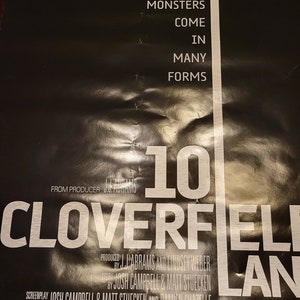 Puede incluir: Un p&oacute;ster de pel&iacute;cula en blanco y negro para la pel&iacute;cula "10 Cloverfield Lane". El p&oacute;ster presenta el t&iacute;tulo de la pel&iacute;cula en letras blancas grandes, con el lema "Los monstruos vienen en muchas formas" en letras blancas m&aacute;s peque&ntilde;as. El p&oacute;ster tambi&eacute;n presenta una peque&ntilde;a imagen de una casa en el fondo.