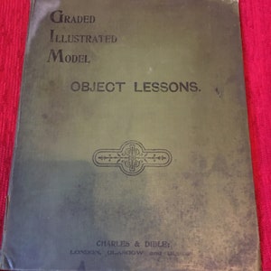May include: A green book cover with the title "GRADED ILLUSTRATED MODEL OBJECT LESSONS." The book is published by Charles & Dible: London, Glasgow and  .