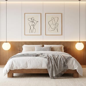 Pode incluir: Um quarto moderno com uma cama de madeira, edredom branco e cobertor cinza. Duas impressões emolduradas de arte de linha abstrata estão penduradas acima da cama. Luminárias pendentes esféricas criam uma atmosfera acolhedora.