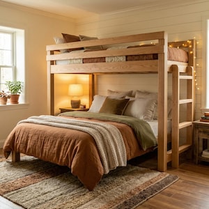 May include: A wooden bunk bed with a ladder, featuring a lower bed with a rust-colored comforter and a cream-colored throw blanket. The upper bunk has a similar rust-colored comforter. The room has a neutral color palette with a rug and a side table.