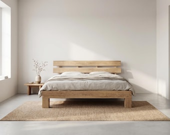May include: A light brown wooden bed frame with a horizontal slat headboard, featuring a neutral-toned duvet and pillows. The bed is positioned on a rectangular woven rug, with a small wooden side table holding a vase with dried branches.