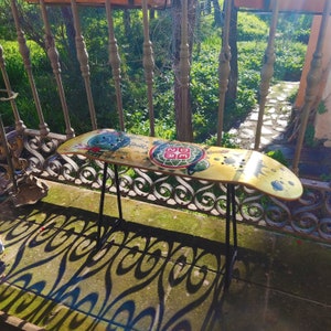 Puede incluir: Una tabla de skate colorida con un marco de metal negro, sentada sobre una superficie estampada. La tabla de skate tiene un diseño de una tortuga con las palabras "202" en su caparazón.