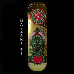 May include: Gold skateboard deck with a green and red design featuring a stylized face with a headdress. The text "DEZA BEATZ" is printed on the bottom of the deck.