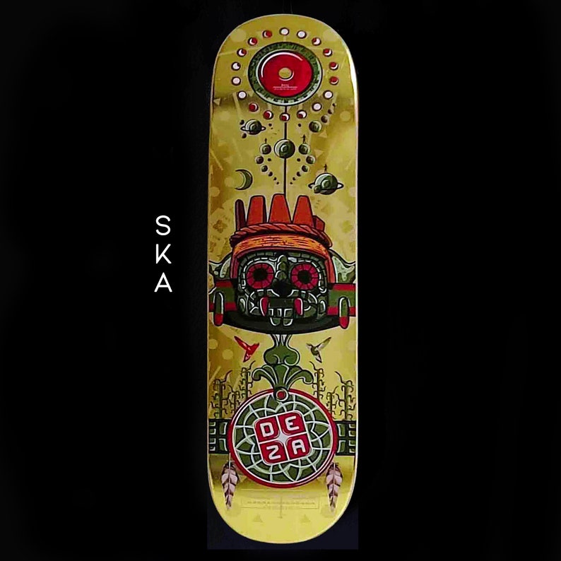 May include: A yellow skateboard deck with a green, red, and gold design. The design features a stylized face with large eyes and a crown. The text "DEZA" is in a red square on the bottom of the deck.