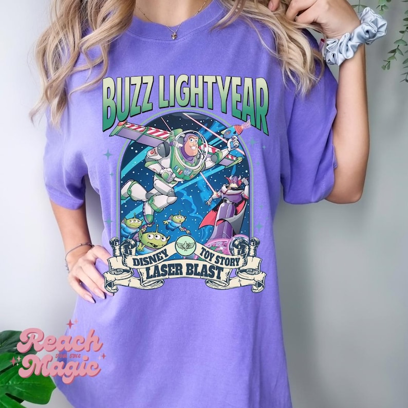 K&ouml;nnte beinhalten: Lilafarbenes T-Shirt mit einem Aufdruck von Buzz Lightyear aus Toy Story. Der Aufdruck enth&auml;lt den Text "Buzz Lightyear", "Disney", "Toy Story" und "Laser Blast".
