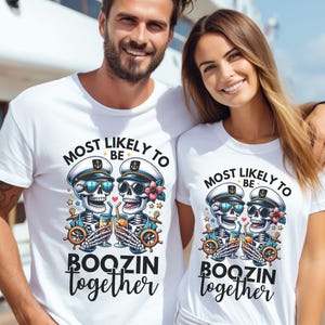 May include: Two white t-shirts with a skull and crossbones design. The text on the shirts reads "Most Likely To Be Boozin Together".