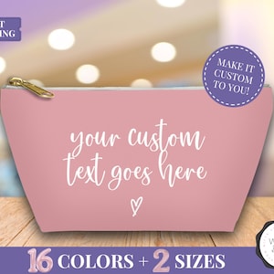 May include: A pink cosmetic bag with a gold zipper, featuring the text "your custom text goes here" in white script, and a small heart. The bag has a rounded shape and includes the text "16 COLORS + 2 SIZES".