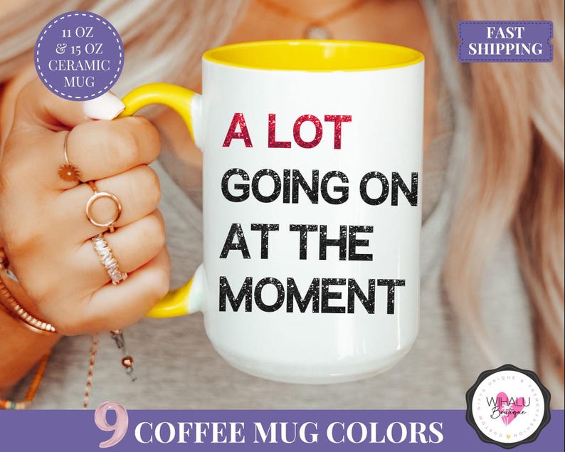 Puede incluir: Taza de cer&aacute;mica blanca con asa e interior amarillos. La taza presenta el texto "A LOT GOING ON AT THE MOMENT" en negro y rojo. La taza est&aacute; disponible en 9 colores y es una taza de cer&aacute;mica de 325 ml o 444 ml.