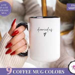 May include: White ceramic coffee mug with a black handle and rim. The mug has the text "divorced af" with a heart symbol. The mug is available in 11 oz and 15 oz sizes. The image also shows the text "9 coffee mug colors".
