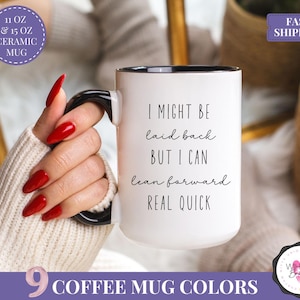 May include: White ceramic mug with a black handle and rim, featuring the text "I MIGHT BE laid back BUT I CAN lean forward REAL QUICK." The mug is available in 11 oz and 15 oz sizes and comes in 9 coffee mug colors.