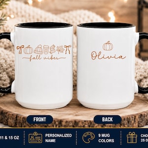 May include: Two white ceramic mugs with black handles and rims. The front mug features orange line art of a pumpkin, beanie, coffee cup, scarf, leaf, and bow with the text fall vibes. The back mug displays a pumpkin and the name Olivia in orange.