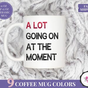 Puede incluir: Taza de caf&eacute; de cer&aacute;mica blanca con el texto "A LOT GOING ON AT THE MOMENT" en negro y rojo. La taza est&aacute; disponible en 9 colores y en tama&ntilde;os de 11 oz y 15 oz.