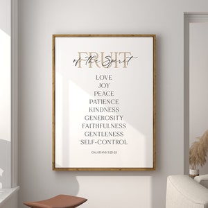May include: A white framed print with the text "Fruit of the Spirit" in brown cursive lettering. The text is followed by a list of nine virtues: love, joy, peace, patience, kindness, generosity, faithfulness, gentleness, and self-control. The scripture reference "Galatians 5:22-23" is printed at the bottom of the print.