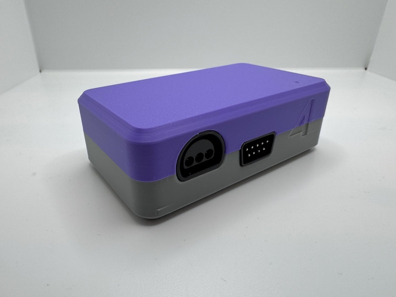 May include: A two-tone, purple and gray rectangular electronic device. The top is purple, and the bottom is gray. It has several ports on the front, including a circular port and a rectangular port. The number "4" is printed on the side.