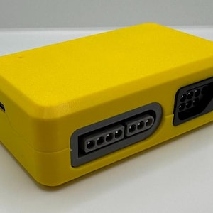 May include: A bright yellow rectangular electronic device with multiple ports. The device has a textured surface and a dark gray port panel with multiple pin connectors. A USB port is visible on the side.