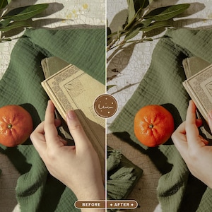 May include: A flat lay image of a green fabric with a book and an orange. The book has a decorative cover with a floral design. The orange is in the lower left corner of the image.