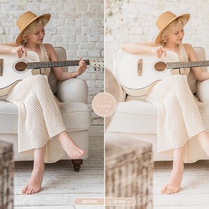 May include: A white acoustic guitar with a dark fretboard and bridge, held by a person wearing a tan wide-brimmed hat and a cream-colored textured knit dress, seated in a light-colored upholstered armchair against a white brick wall.