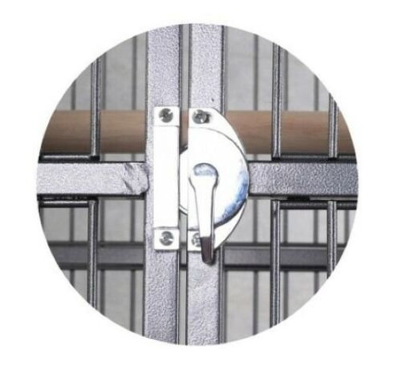 May include: A silver metal bird cage door latch featuring a rotating handle mechanism mounted on a gray wire frame. The latch is secured with visible screws and positioned horizontally across the cage bars, with a light brown wooden perch visible.