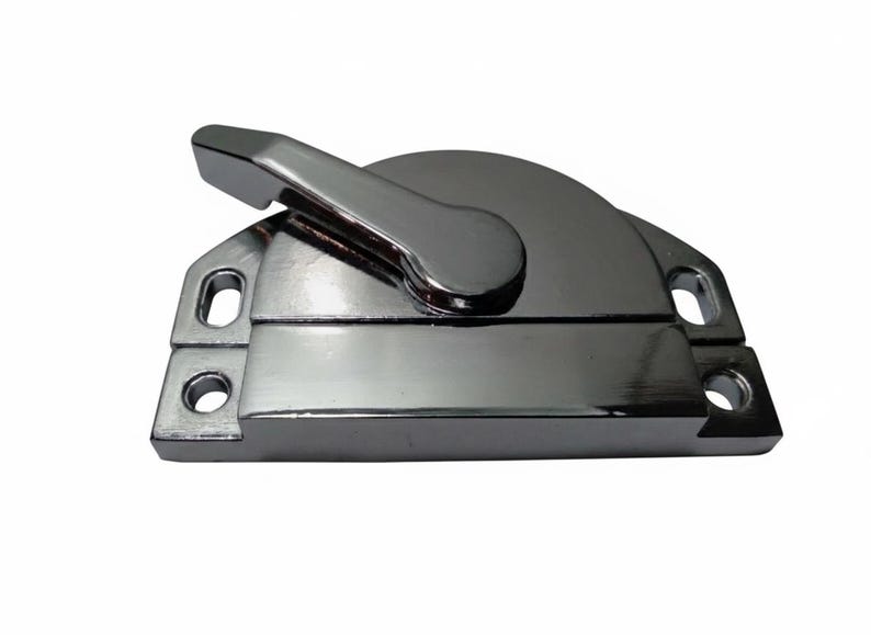 May include: A polished chrome window sash lock featuring a rectangular base with two mounting holes on each side and a rotating lever arm that secures the mechanism. The metallic finish is reflective and smooth, showing a clean, industrial design.