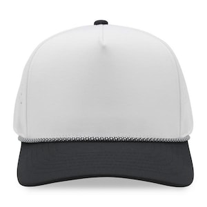 May include: A white trucker hat with a black brim and a black button on top. The hat has a white front panel and a black and white rope detail along the brim.
