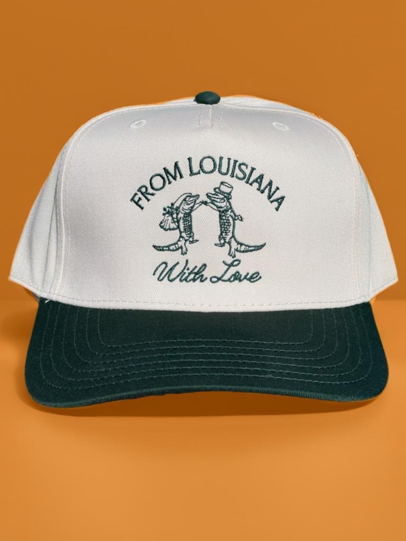 Custom Embroidered Hat – Personalized Hats for Bachelorette Party, Bridesmaid Gifts, Wedding Party & Bulk Business Orders. The hat in this image is a custom hat made for a couple. It features two dancing alligators on a natural/dark green hat with the words: From Louisiana With Love on an orange background.