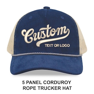 May include: A navy blue corduroy trucker hat with a beige mesh back. The hat features the word "Custom" in a cursive font, with the text "TEXT OR LOGO" below. The bottom of the hat reads "5 PANEL CORDUROY ROPE TRUCKER HAT".