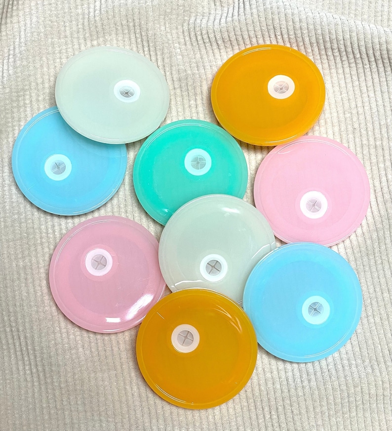 May include: Nine round, colourful lids with a small hole in the centre. The lids are in shades of blue, green, yellow, and pink.