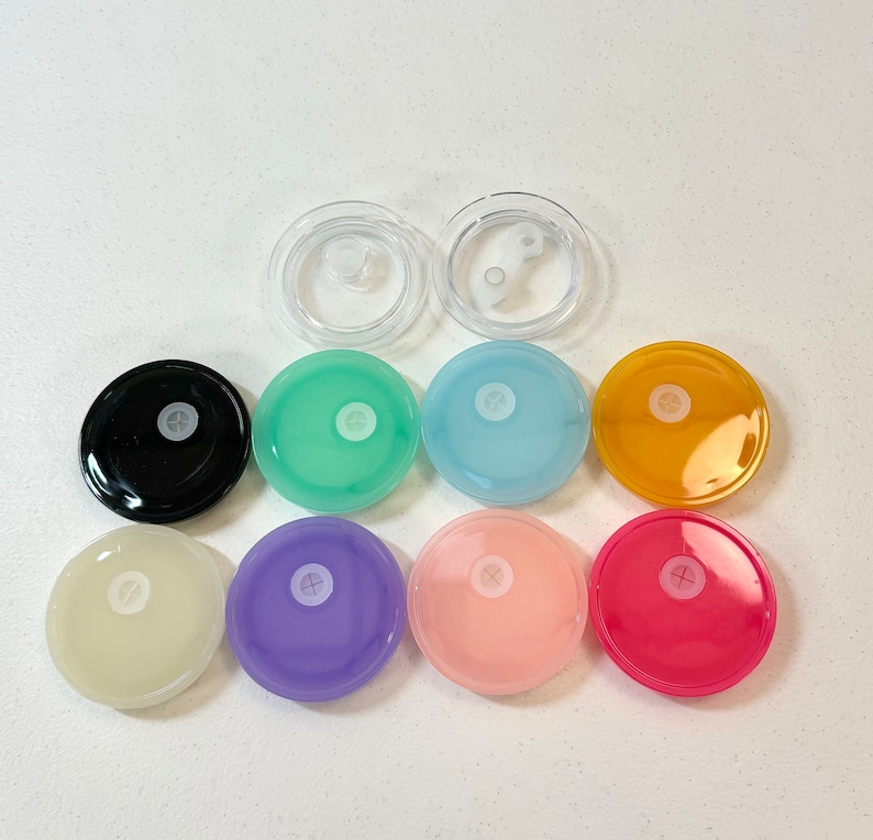 May include: Assortment of ten round, colourful lids with a small hole in the centre. The lids are in various colours, including black, green, blue, yellow, pink, and purple. Two clear plastic lids are also included.