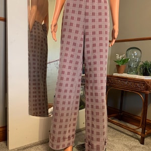 May include: Burgundy and white plaid pants with a wide leg. The pants have an elastic waistband and are displayed on a mannequin. The fabric has a soft texture. The pants are a vintage style.