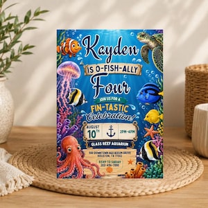 May include: A rectangular birthday invitation card featuring a vibrant underwater scene with a clownfish, sea turtle, jellyfish, octopus, and various tropical fish. The text reads Kayden is O-Fish-Ally Four, Join us for a Fin-Tastic Celebration.