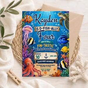 May include: A rectangular birthday invitation card featuring an underwater theme with a clownfish, sea turtle, jellyfish, octopus, and various tropical fish. The text reads: Kayden is o-fish-ally four, join us for a fin-tastic celebration, August 10th, 2pm-4pm.