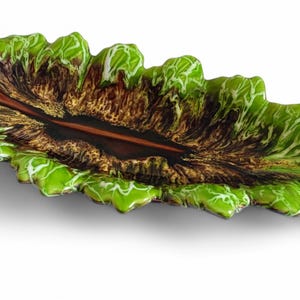 Puede incluir: Un plato de servir en forma de hoja verde y marrón con un diseño marmoleado blanco y marrón. El plato está hecho de vidrio y tiene una forma orgánica única.