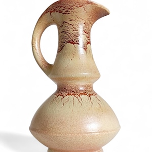Può includere: Brocca in ceramica con manico e beccuccio. La brocca ha un colore di base beige con accenti marroni e una superficie strutturata. Il design è in stile vintage, adatto per uso decorativo.