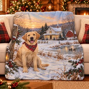 May include: A soft throw blanket featuring a golden Labrador retriever wearing a red and green plaid bandana, sitting in a snowy landscape with a house, a frozen pond with ducks, and evergreen trees decorated with red berries in the foreground.