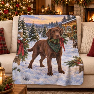 Peut inclure: Un plaid doux illustré d'un Labrador chocolat debout dans une forêt enneigée. Le chien porte un bandana à carreaux verts et tient des branches de pin avec un ruban rouge dans la gueule. Le fond montre des arbres couverts de neige.
