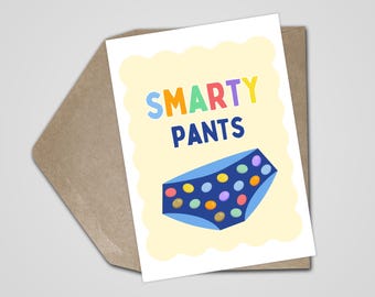 May include: A greeting card featuring the words "SMARTY PANTS" in bright colours. Below the text is a blue cartoon pair of underpants decorated with colourful spots. The card is in a brown envelope.
