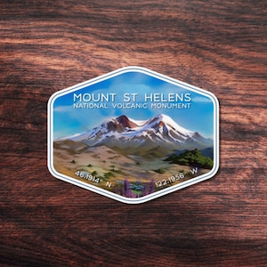 May include: A blue and white sticker with a mountain scene and the text "MOUNT ST. HELENS NATIONAL VOLCANIC MONUMENT" and coordinates "46.1914° N 122.1956° W".