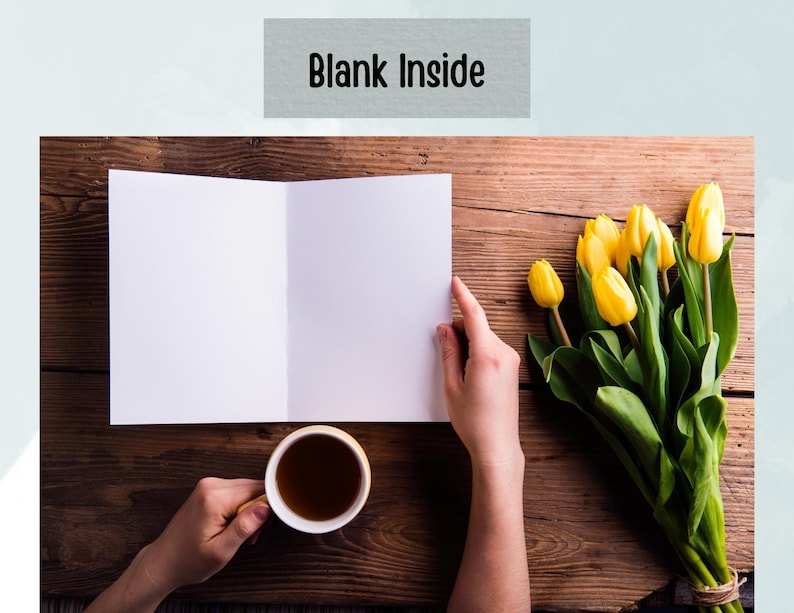 May include: A blank white card folded in half, with a cup of tea and a bouquet of yellow tulips on a wooden table. The card has the words "Blank Inside" printed on the front.