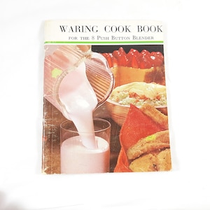 May include: A vintage Waring Cook Book for the 8 Push Button Blender. The cover features a pink milkshake being poured into a glass, with other food items like a salad and a dessert in the background.
