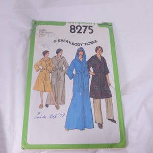 May include: A vintage Simplicity sewing pattern, number 8275, for "E Every-Body Robes." The pattern envelope features illustrations of robes in various colors and styles. The text includes "SMALL EVERYBODY CHEST 32" and "Linda Och '78."