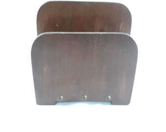 May include: A dark brown wooden magazine rack with a simple design. The rack has two compartments and is held together by small screws.