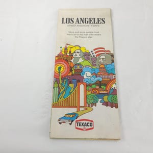 May include: Vintage Los Angeles street and vicinity map. The cover features colorful illustrations of landmarks, a car, and the Texaco logo. The text reads "More and more people trust their car to the man who wears the Texaco star."